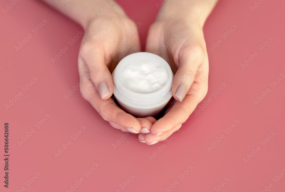 A jar of skin cream in the palms on a uniform background. The concept of face or hand skin care with natural cream. Cosmetic for body care. Free space for advertising and text A jar of skin cream in the palms on a uniform background. The concept of face or hand skin care with natural cream. Cosmetic for body care. Free space for advertising and text