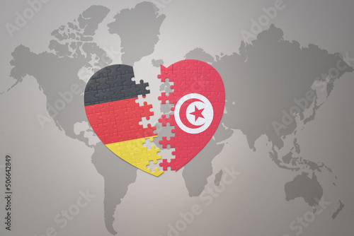 puzzle heart with the national flag of tunisia and germany on a world map background. Concept. photo