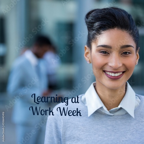 Portrait of smiling biracial young businesswoman with learning at work week text in office