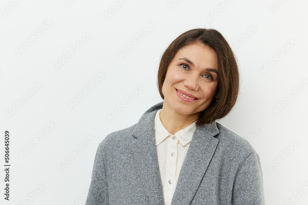 portrait of a cute, happy, pleasant woman smiling happily at the camera while standing in a gray coat on a pale background with an empty space for an advertising mockup portrait of a cute, happy, pleasant woman smiling happily at the camera while standing in a gray coat on a pale background with an empty space for an advertising mockup