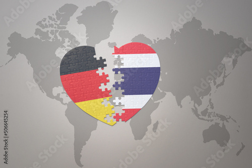 puzzle heart with the national flag of thailand and germany on a world map background. Concept.