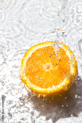 Water pours on an orange on a white background. Refreshing orange. Juicy fresh orange