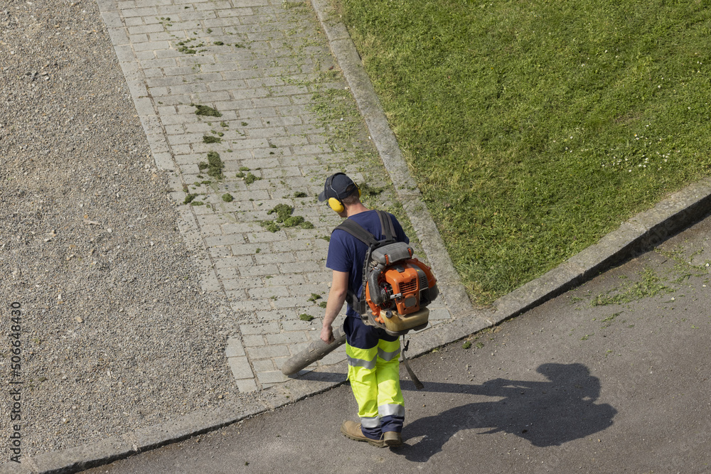 Fototapeta premium Jardinier en train de nettoyer une allée d'un espace vert