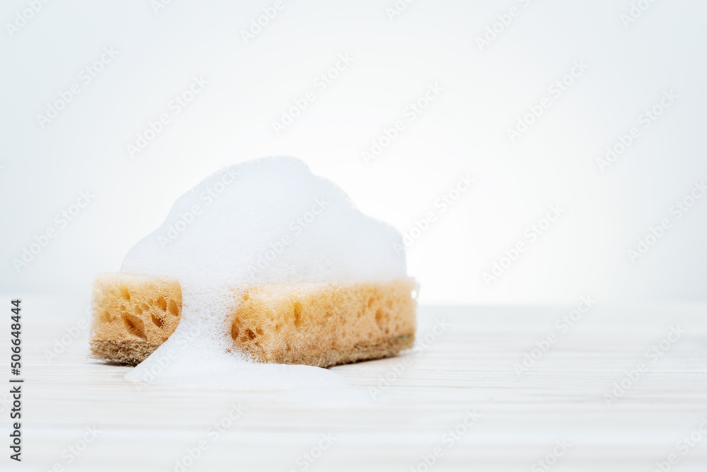 soapy sponge on white bathroom tiles.