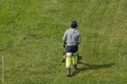 Jardinier en train de tondre un gazon d'un espace vert 