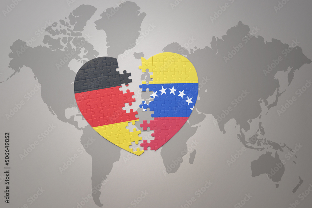 Naklejka premium puzzle heart with the national flag of venezuela and germany on a world map background. Concept.