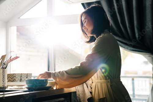 Asian woman wearing robe smiling while cooking at home