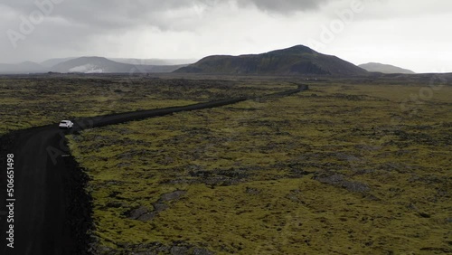 White 4X4 off road vehicle driving along volcanic dirt road in Iceland. Stunning cinematic drone shot showing Icelandic landscape. photo