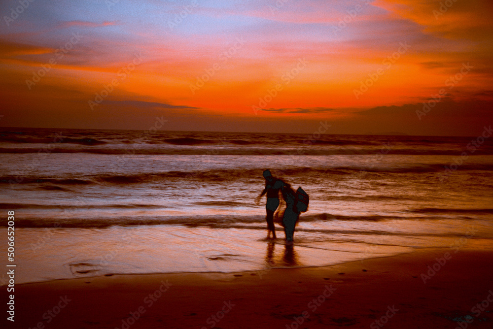 Naklejka premium Paints of the Indian Ocean in the evening. Silhouettes of people on the shores of the Indian Ocean during sunset.