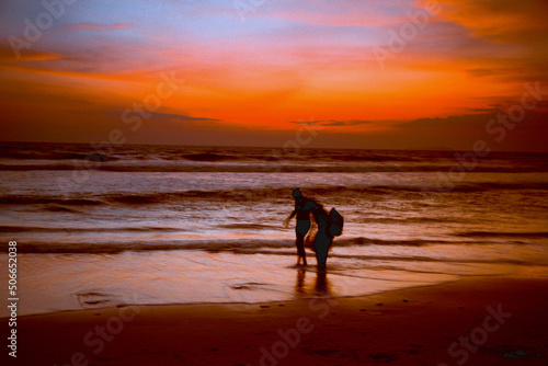Paints of the Indian Ocean in the evening. Silhouettes of people on the shores of the Indian Ocean during sunset.