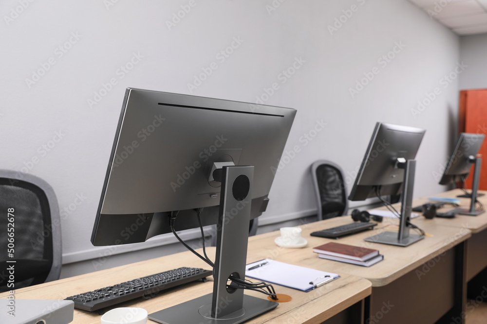 Open office interior. Modern workplaces with computers near light grey wall Open office interior. Modern workplaces with computers near light grey wall