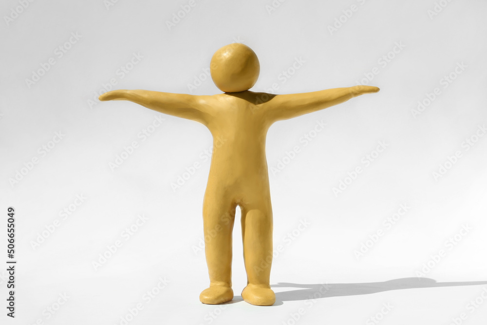 Human figure with arms wide open made of yellow plasticine on white background Human figure with arms wide open made of yellow plasticine on white background