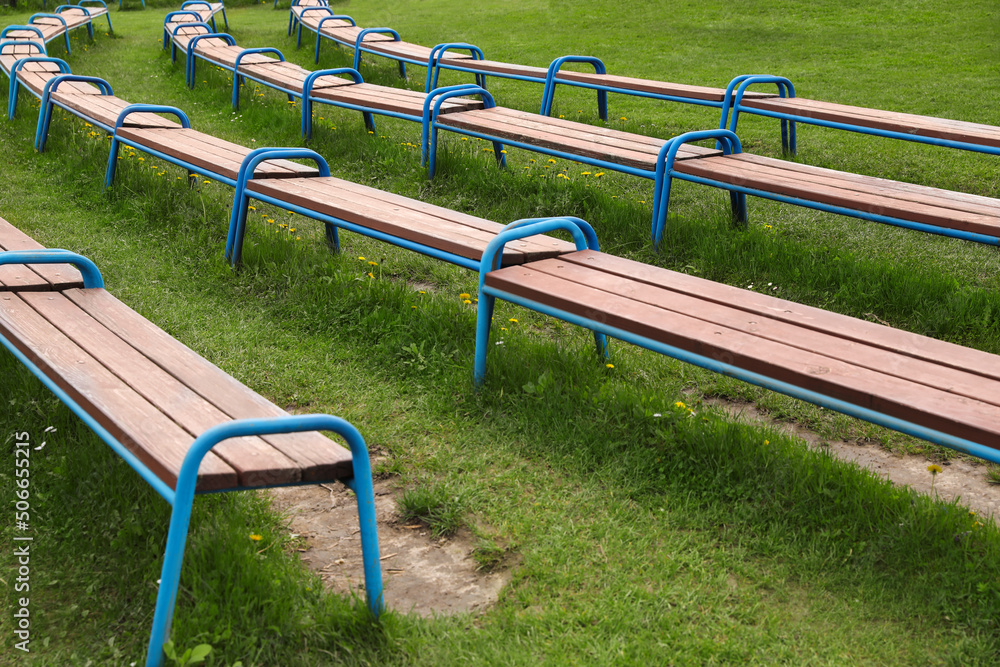 Modern wooden benches on green grass in park Modern wooden benches on green grass in park