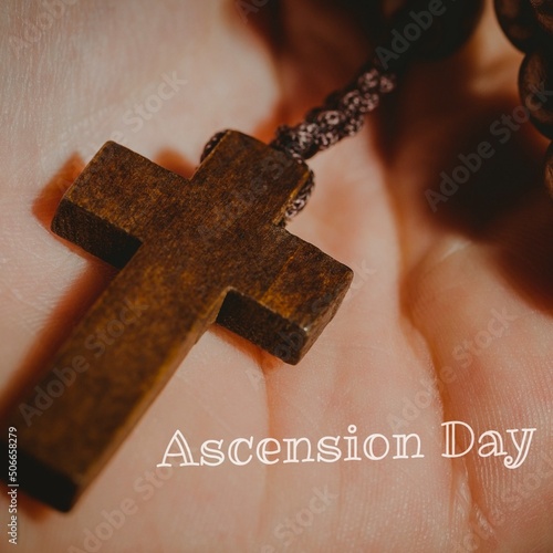 Ascension day text with cropped hand of person holding wooden cross, copy space