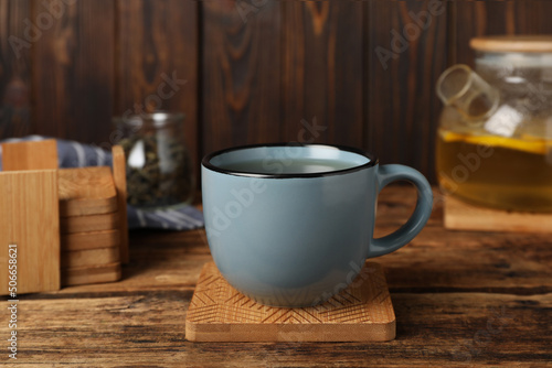 Photo Mug of hot drink and stylish cup coaster on wooden table