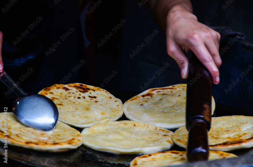 Fototapeta premium Man baking roti on the fried oil. Parathas are being baked in big dish
