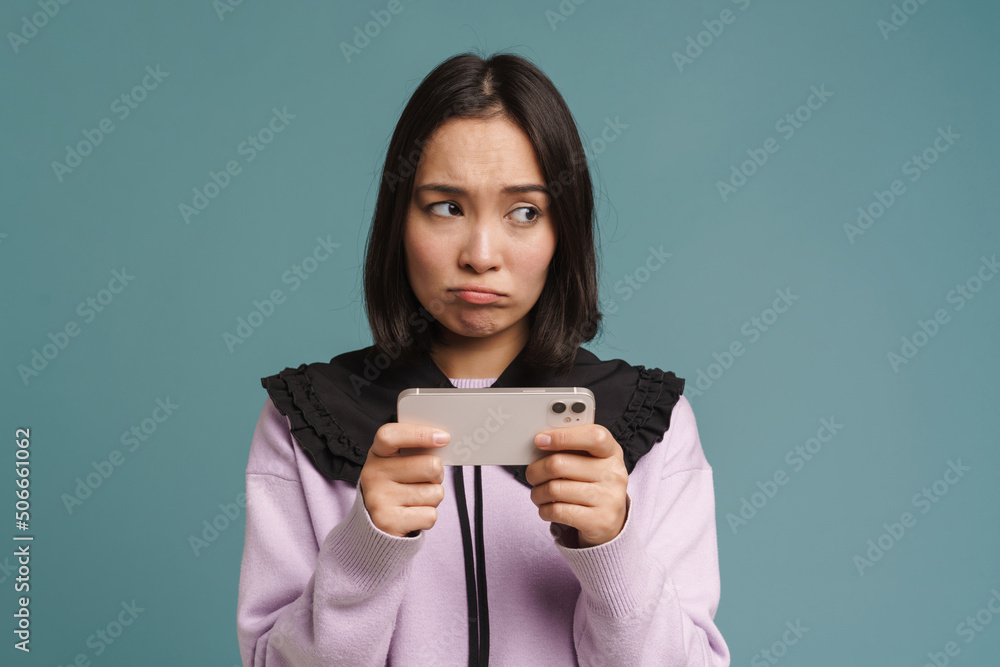 Young asian woman playing online game on mobile phone Young asian woman playing online game on mobile phone