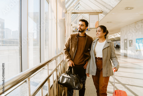 Tableau sur toile Young indian couple looking in window together at airport