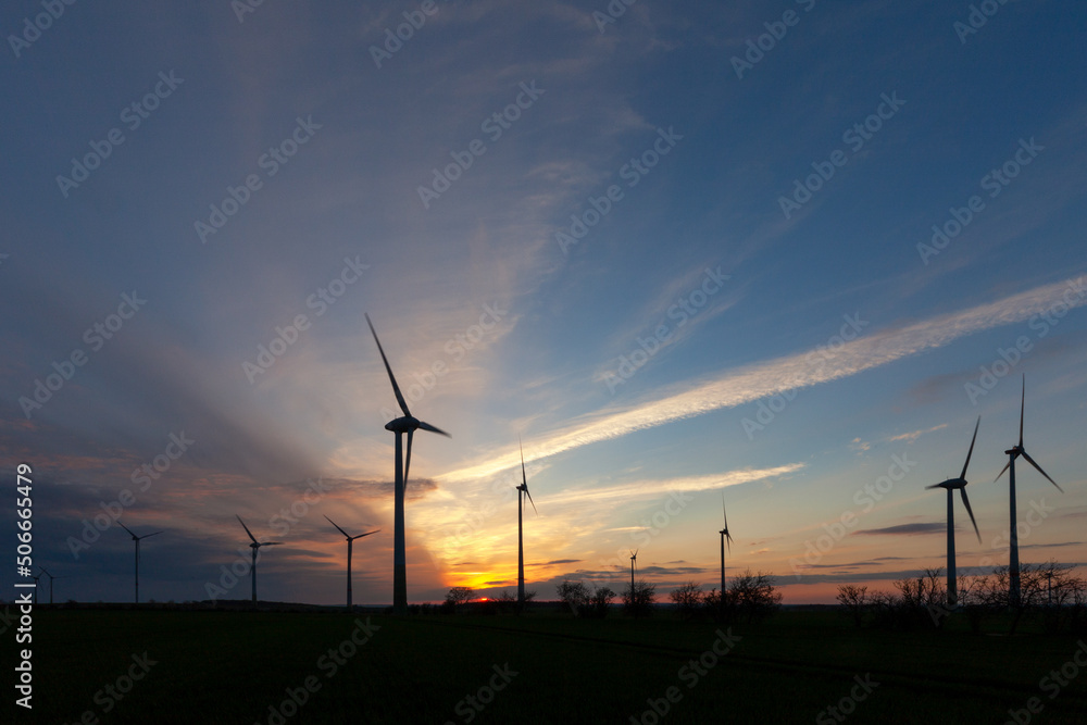 Obraz premium Windräder als Silhouette im romantischen Sonnenuntergang auf einem Feld - Sachsen-Anhalt in Deutschland