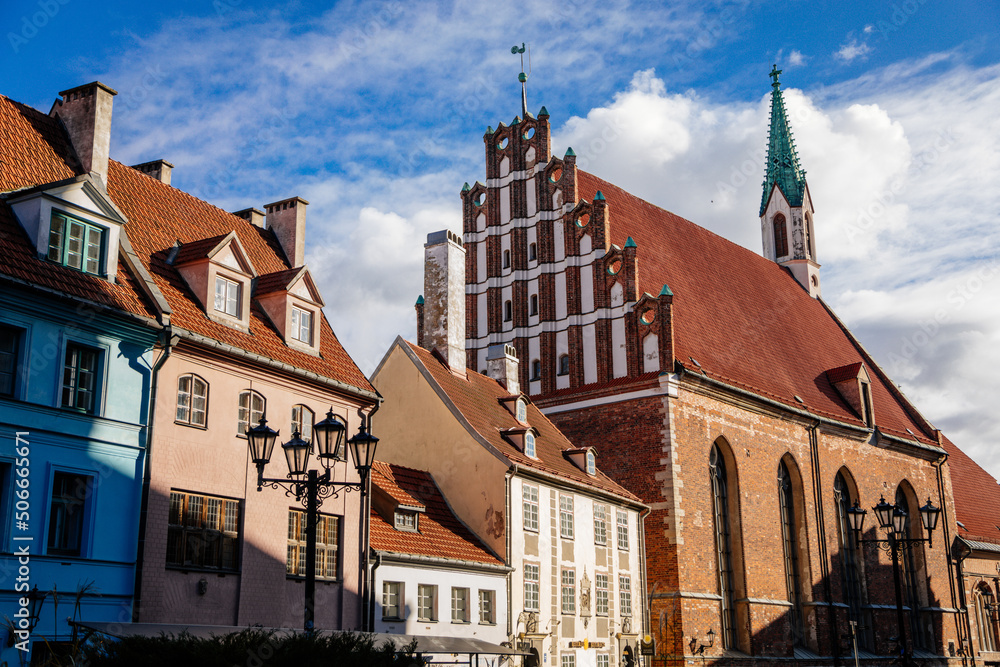 Fototapeta premium Riga, Latvia, 19 October 2021: St. John's Church, UNESCO heritage in Baltic states, Northern Gothic Style with Red brick and spire, recognizable medieval landmark at old town at sunny day