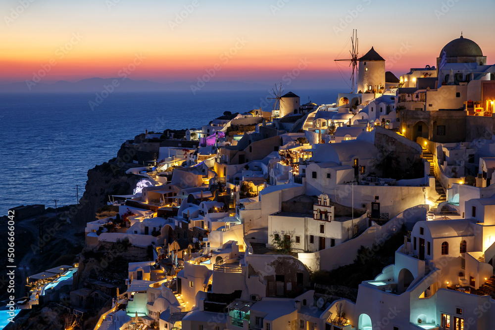 Santorini famous view with white houses and windmill during sunset. Vacation in Greece on the Aegean sea.