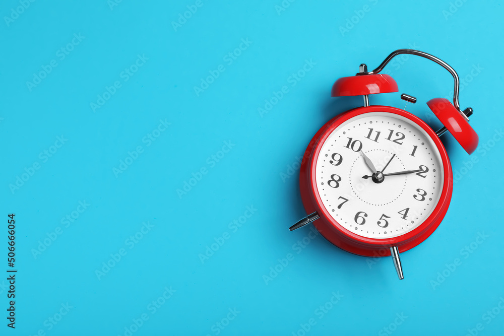 Alarm clock on light blue background, top view with space for text. School time Alarm clock on light blue background, top view with space for text. School time