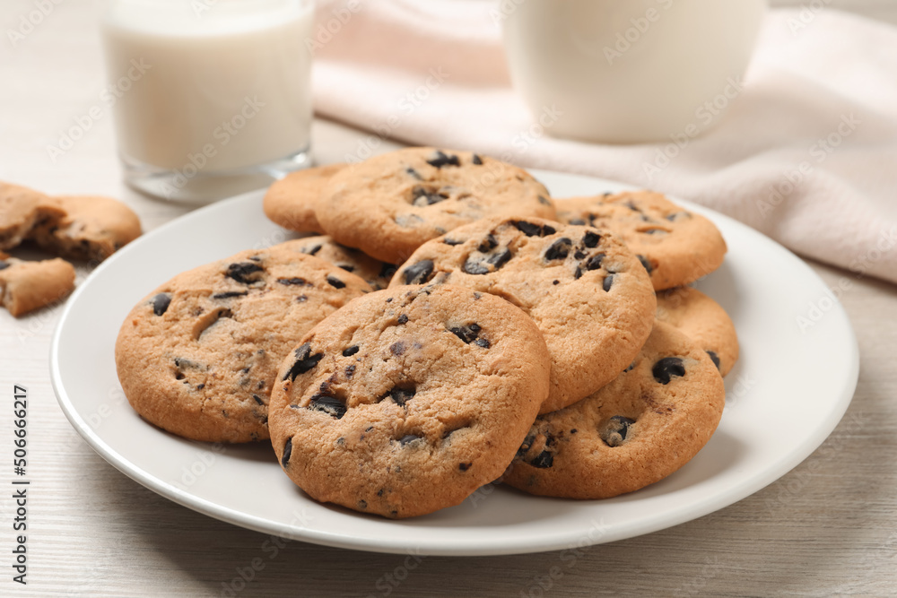 Plate with delicious chocolate chip cookies on white wooden table, closeup Plate with delicious chocolate chip cookies on white wooden table, closeup