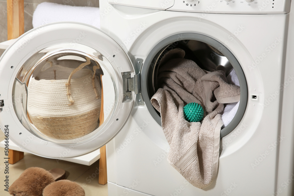 Green dryer ball and towels in washing machine drum indoors Green dryer ball and towels in washing machine drum indoors
