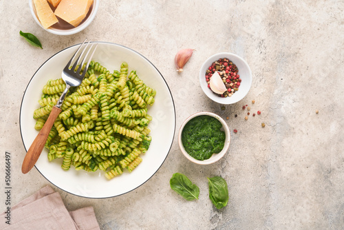 Italian Fusilli Pasta with Pesto. Fusilli pasta with basil pesto and herbs, parmesan cheese, basil and garlic on white plate on grey stone countertop background. Top view. Copy space. Mock up.