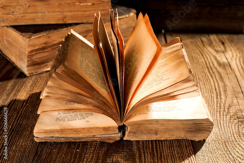 An open vintage book and a stack of old books on a vintage wooden table.