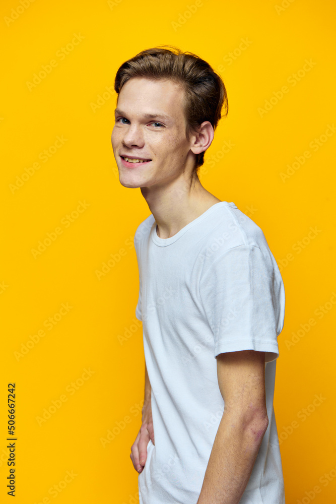 vertical portrait of a cute guy in a light t-shirt on a yellow background vertical portrait of a cute guy in a light t-shirt on a yellow background