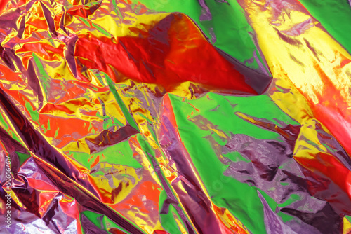 Bright color reflection on surface of cellophane film. Abstract colorful background. Red, green, yellow and purple backdrop.