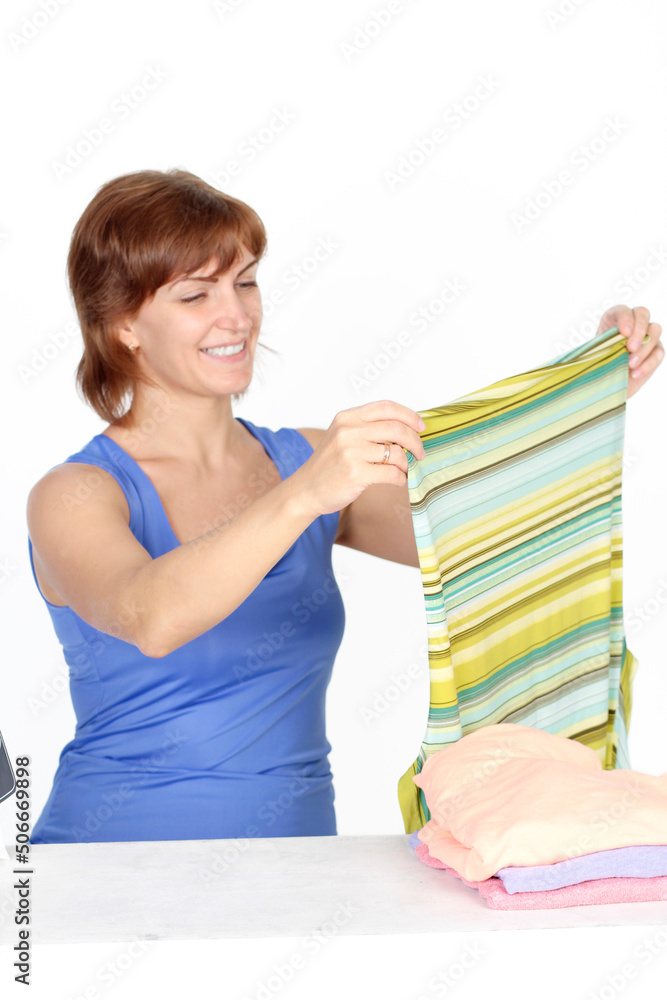 Young smiling woman is ironing a shirt with a shirt iron on white background. Young smiling woman is ironing a shirt with a shirt iron on white background.