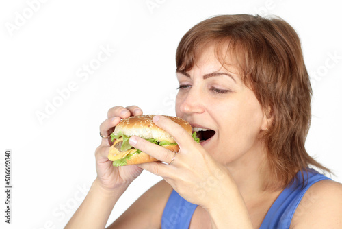 Portrait of young beautiful hungry woman eating burger. Diet concept.