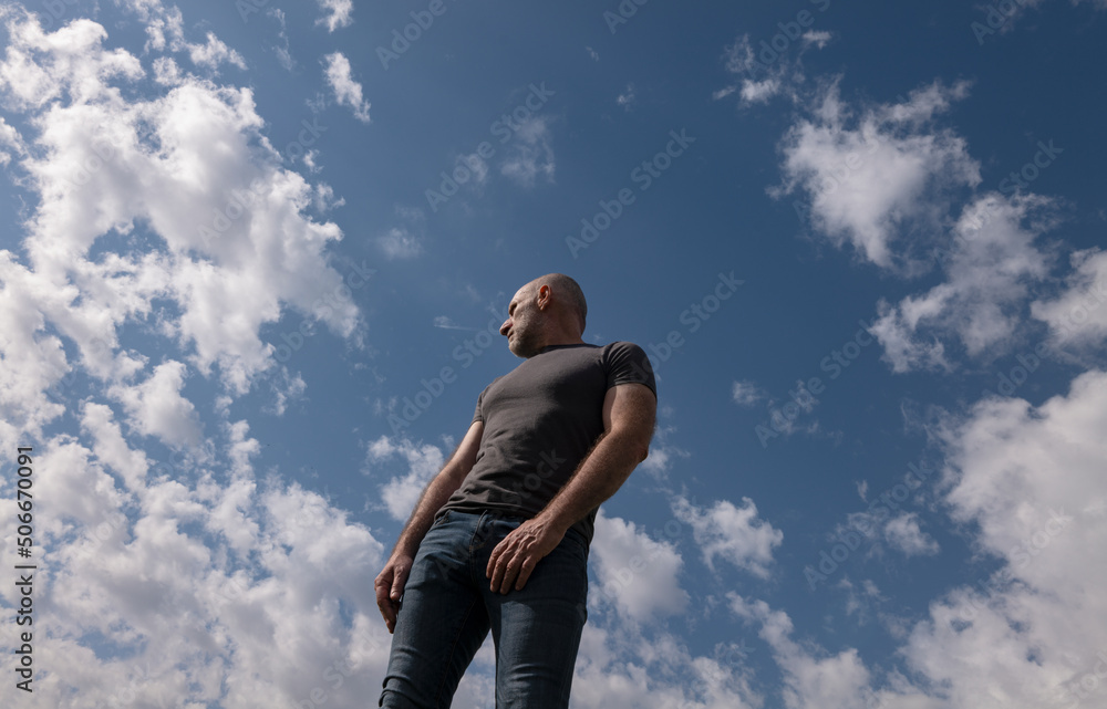 Low angle view of adult man against cloudy sky Low angle view of adult man against cloudy sky