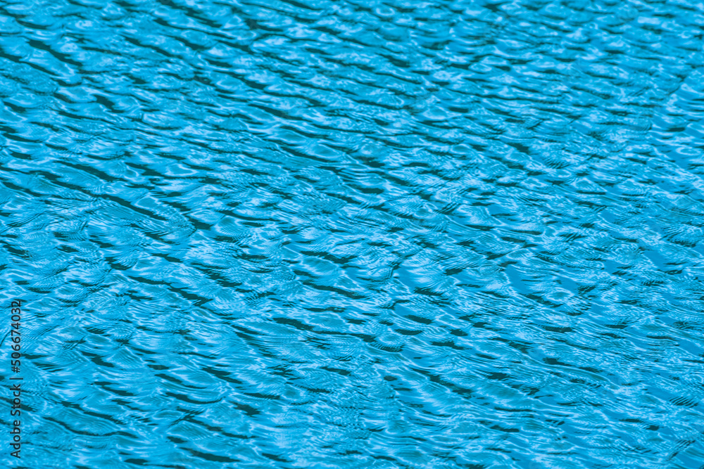 bluewater surface By the wind. The water surface was ruffled by the light wind with small waves running diagonally, with reflections and graduated from light and blue tones. 
