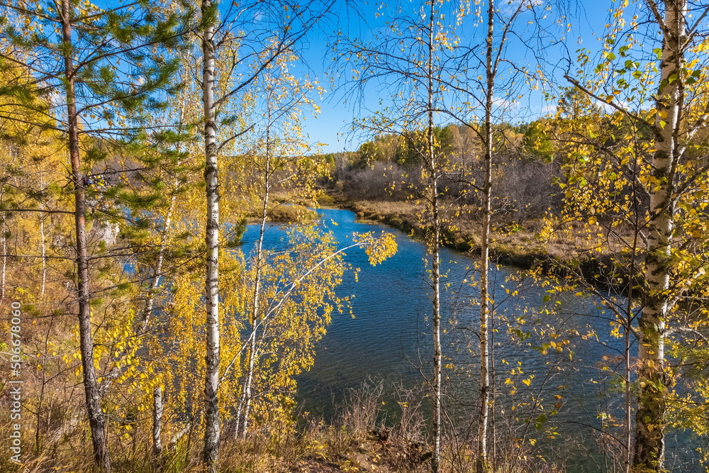 Fototapeta premium Autumn landscape with river, trees, grass and blue sky