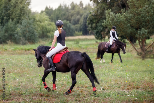Two Jockey girl doing horse riding on countryside meadow