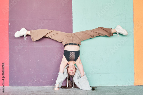 Photography Full length powerful woman in casual wear performing handstand with split near c