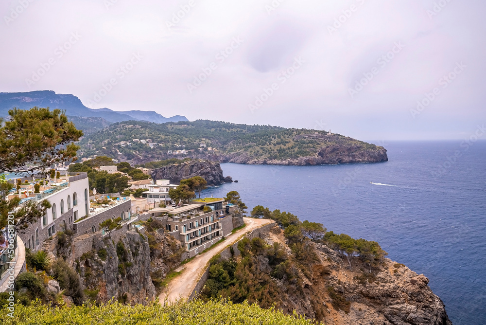 Idyllic view of Mediterranean seascape and houses on rocky cliff. High angle view of beautiful ocean against cloudy sky. Scenic island during summer.
