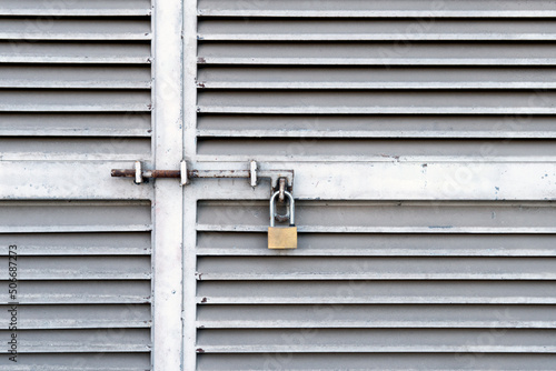 Small padlock hanging on closed metal doors