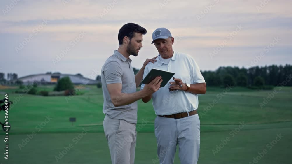 Modern sportsmen holding tablet browsing web on golf field. Online concept. Modern sportsmen holding tablet browsing web on golf field. Online concept.