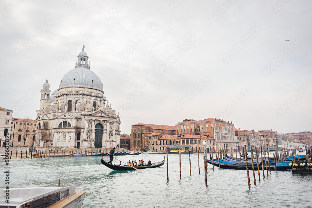 The famous Venetian gondola cruising along the Grand Canal past the basilica Santa Maria della Salute on a cloudy winter day