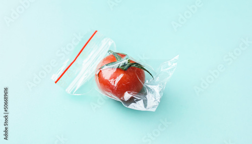 Принти на полотні Red tomato in a zip bag on a green background, the concept of excess food packag