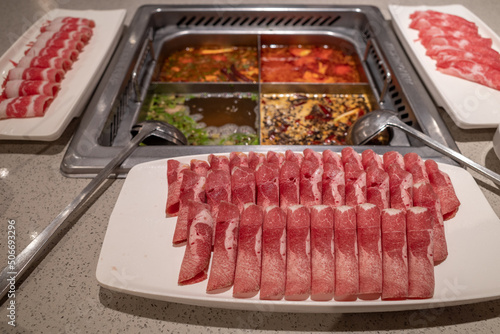 Selective focus view at slice of beef and pork beside mala hotpot and various type of soup.  photo