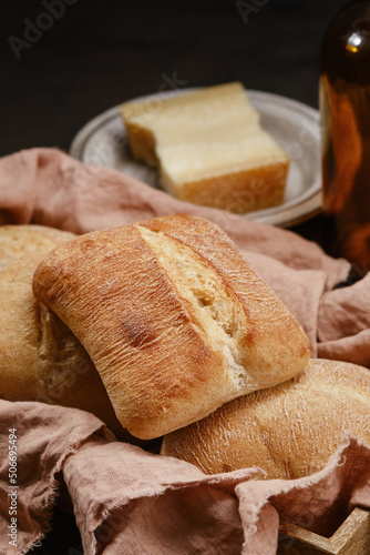 Italian ciabatta bread or bun in a wooden box with pink kitchen towel. Freshly baked traditional bread. Homemade rustic atisan bread or Italian Ciabatta. Shallow depth of field photo