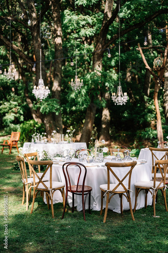 magical rustic wedding tables outside in the garden with hanging light and flowers, chairs, outdoor ceremony in the open air
 photo