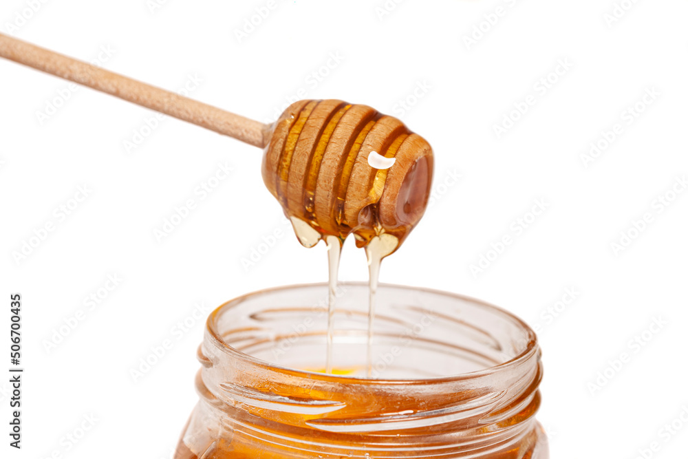 Honey dripping from honey dipper in glass jar. Healthy food concept Honey dripping from honey dipper in glass jar. Healthy food concept