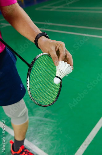 A badminton player serving the shuttlecock © tewpai