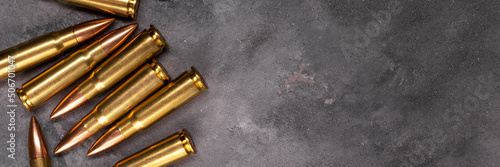 Bullets on gray background banner with copy space. Cartridges 7.62 caliber for Kalashnikov assault rifle. Panoramic web header. Wide screen wallpaper